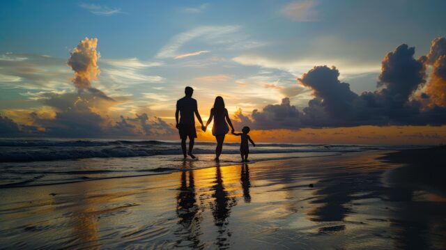 A family of mixed races walking hand in hand, their silhouettes cast on the beach at sunrise